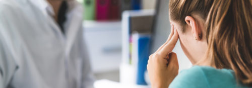 Woman suffering from bad headache or migraine. Appointment with doctor in office room