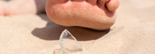 Person stepping on glass shard on Florida beach.