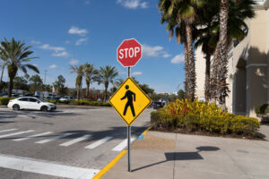 A stop sign with a Pedestrian Crossing Sign outside a shopping mall is shown in Orlando, Florida, USA.