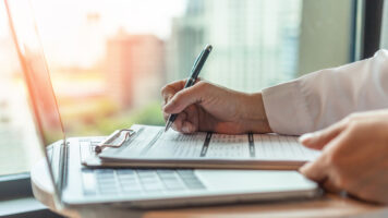 Administrator's hand fill in business schedule form document writing on yearly work plan, monthly timetable sheet, or weekly time table paper for office tasks, things and jobs to do list